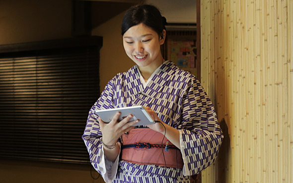 陣屋様のスタッフさんのお写真(2):館内のスタッフさんがタブレットで他のスタッフさんとの情報共有をしている